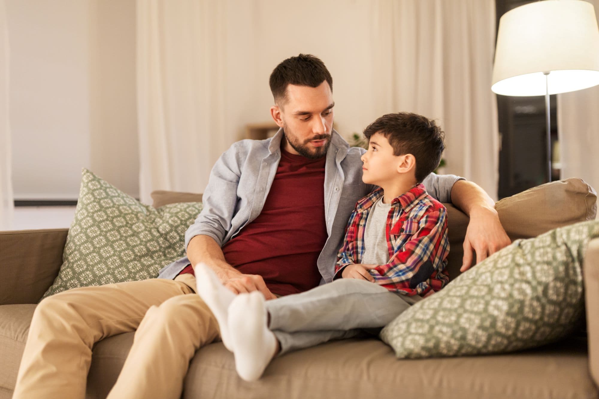 A man and a boy are seated together on a couch, sharing a moment of relaxation and companionship.