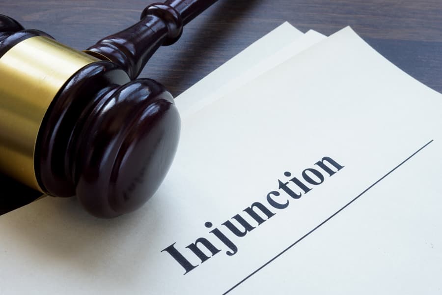 A gavel resting beside a document titled 'Injunction,' symbolizing legal action and justice. Burton Family Attorneys.