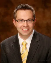 Michael Lundberg, an associate attorney at Burton Law Firm, P.C., dressed in a suit and tie with a vibrant yellow tie.