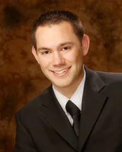 Peter E. Bracken, a senior associate attorney at Burton Law Firm, P.C., poses with a smile in a formal suit and tie.