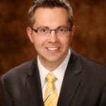 Michael Lundberg, an associate attorney at Burton Law Firm, P.C., dressed in a suit and tie with a vibrant yellow tie.