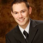 Peter E. Bracken, a senior associate attorney at Burton Law Firm, P.C., poses with a smile in a formal suit and tie.