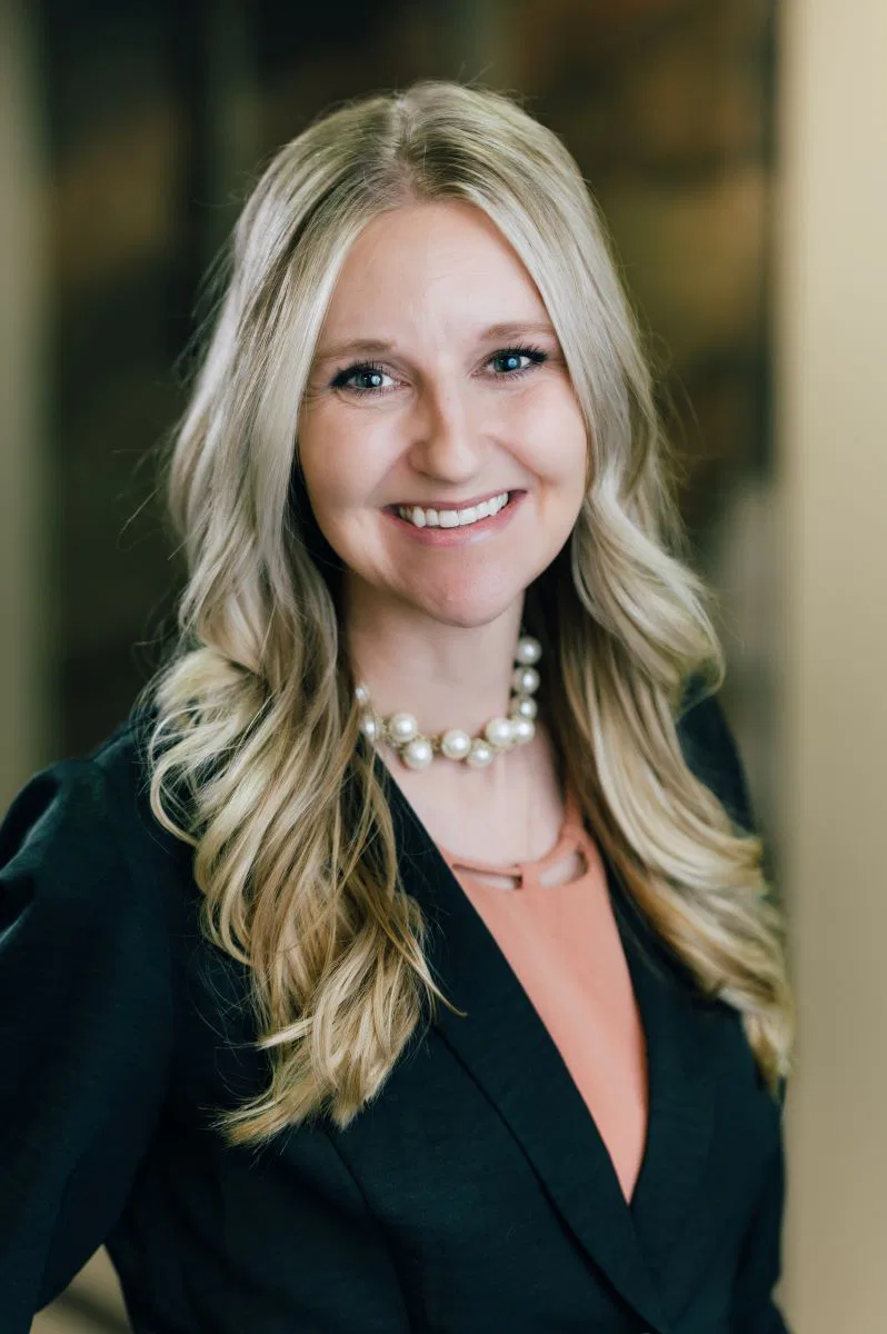 Image of ERIN BARNETT wearing a black business suit and necklace