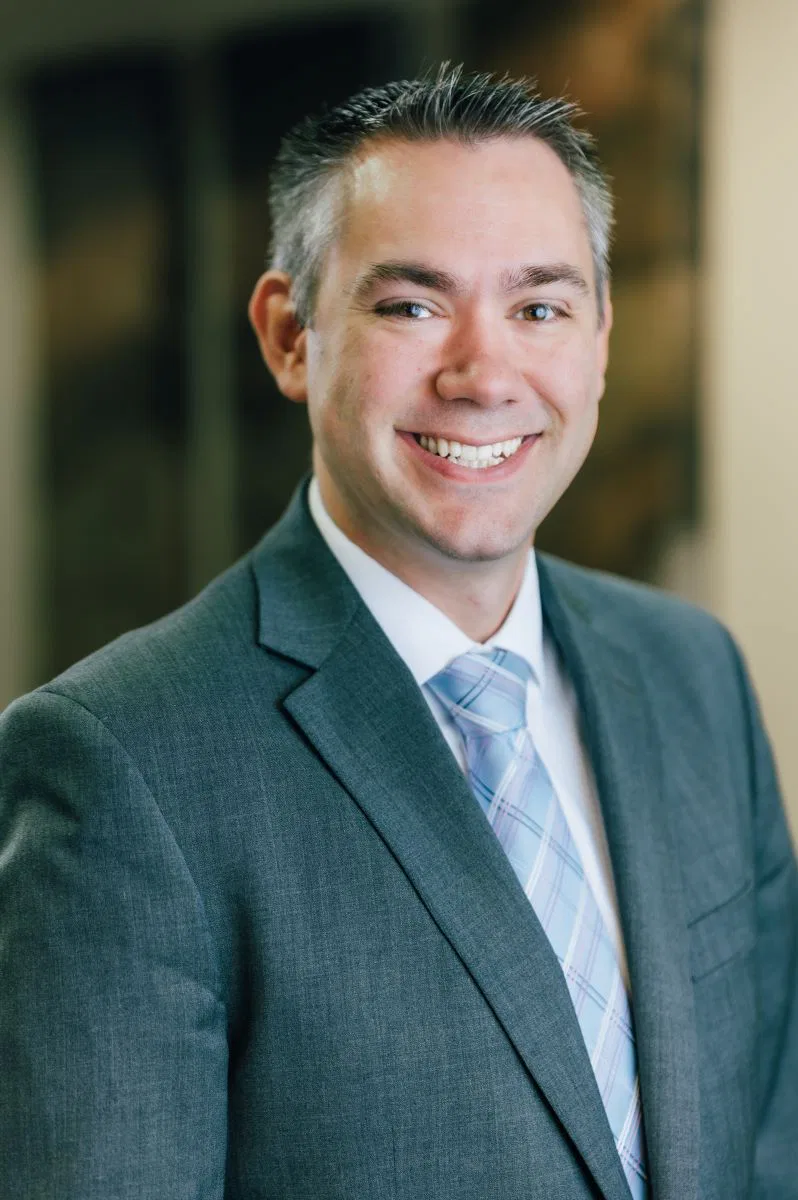 A smiling Peter E. Bracken in a suit and tie poses confidently for the camera.