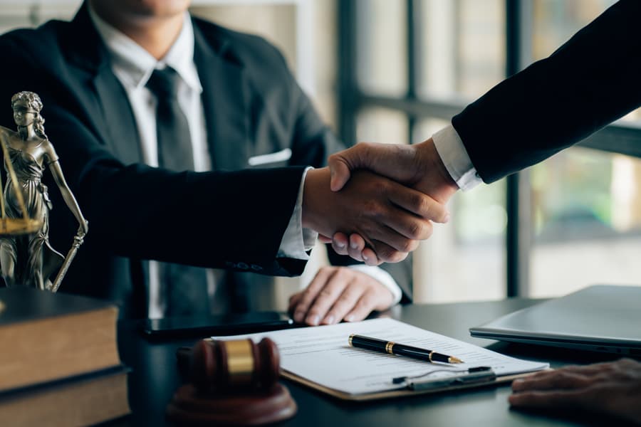 Two professionals shaking hands across a desk, symbolizing the fusion of expertise and empathy in business.