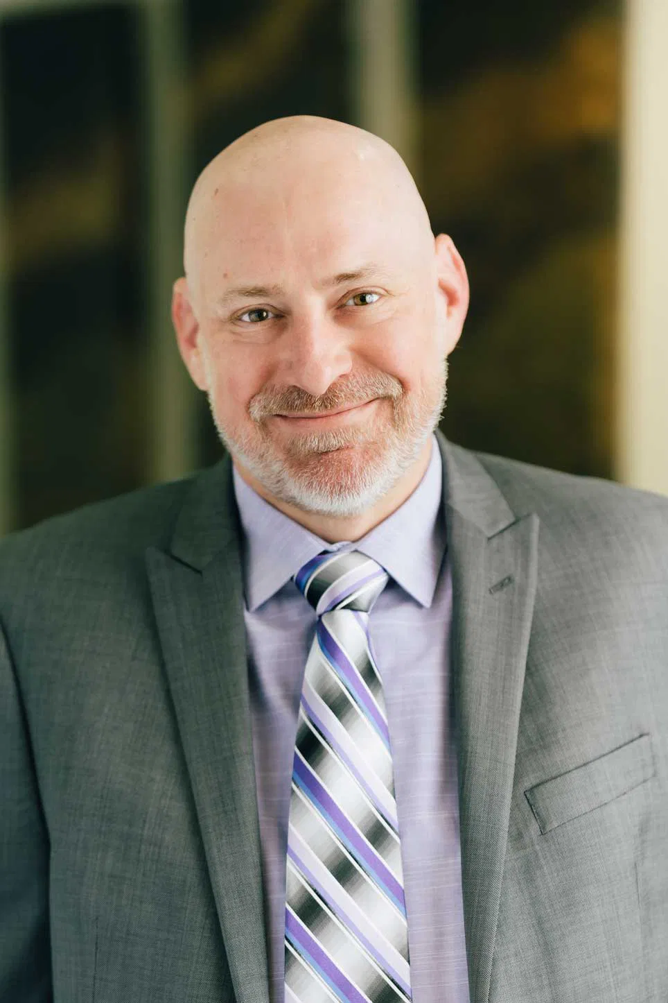 Troy R. Jensen, A bald man dressed in a formal suit and tie, exuding professionalism and confidence.