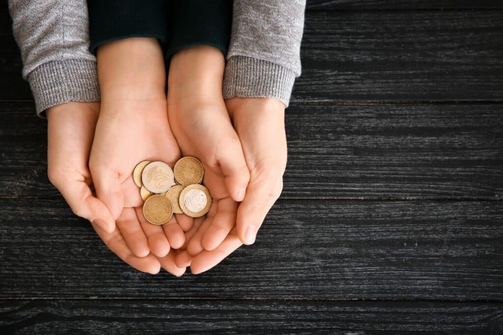 Hands with coins on a wooden table. Financial savings and investment concept