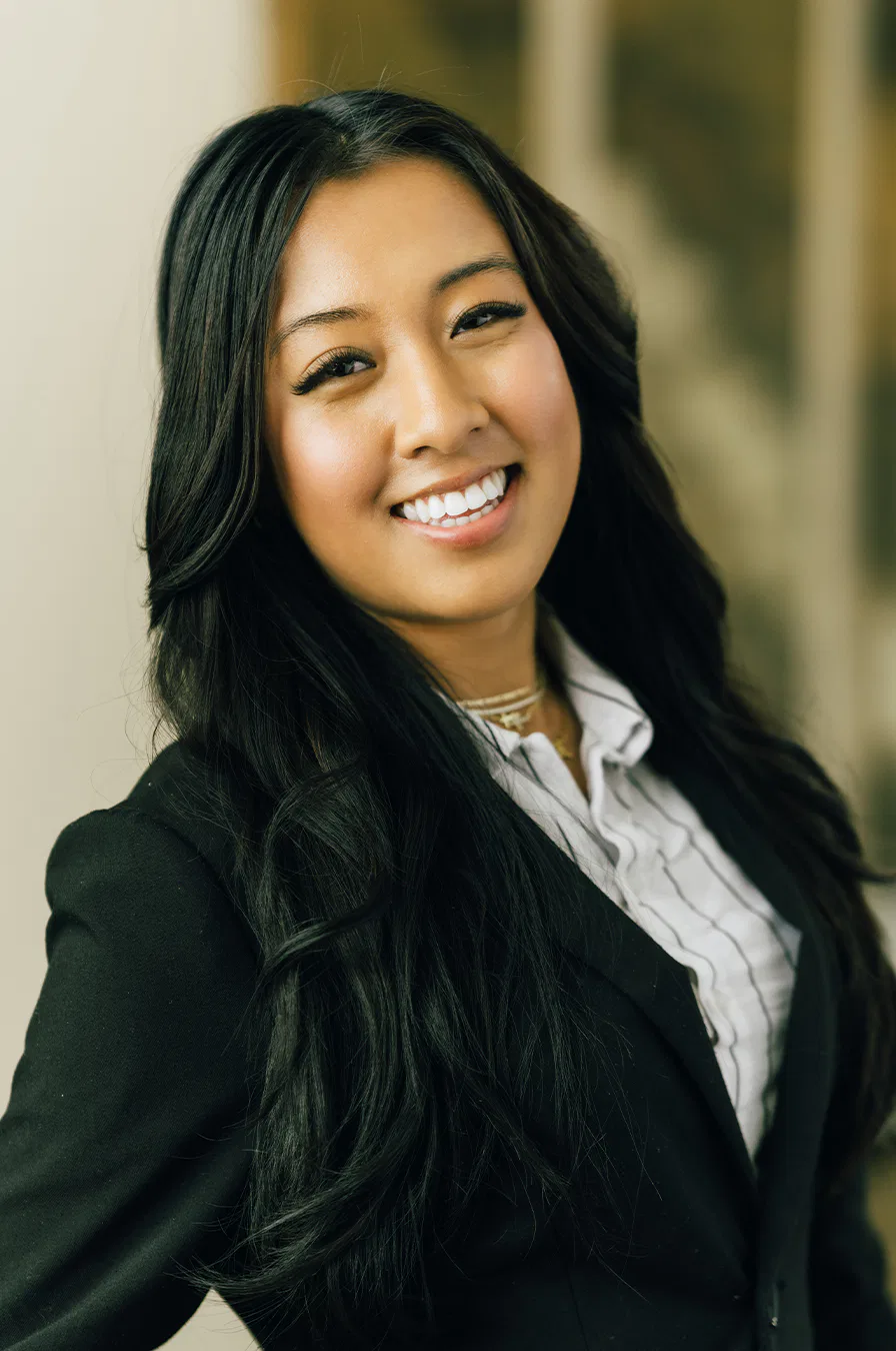 A woman in a business suit smiling confidently, embodying professionalism and positivity in a corporate setting.