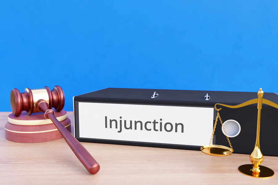 A legal-themed image featuring a gavel, a binder labeled 'Injunction,' and a justice scale on a desk. Burton Family Attorneys.