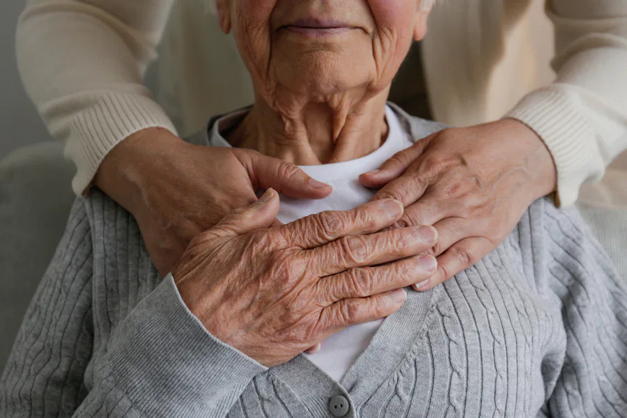 An elderly person's hands being gently held by a younger individual, symbolizing care and support. Burton Family Attorneys.