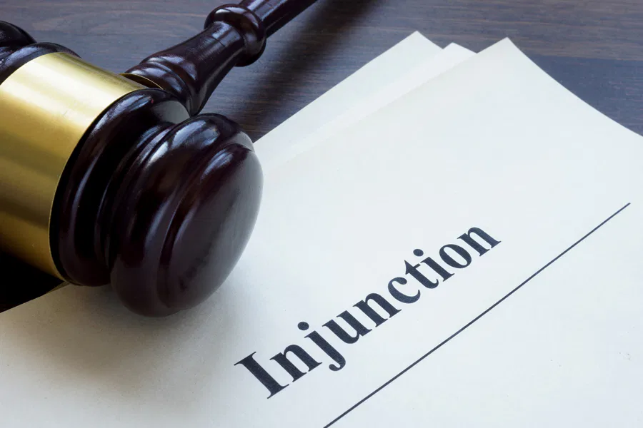 A gavel resting beside a document titled 'Injunction,' symbolizing legal action and justice. Burton Family Attorneys.