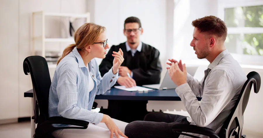 A man and woman engaged in conversation at a table, representing a consultation at Burton Family Attorneys.