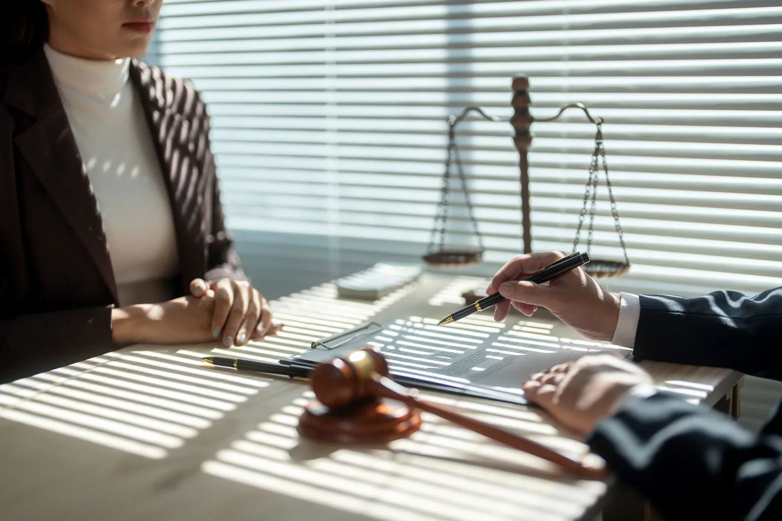 A woman in a business suit signs a document during a divorce consultation with a man, representing Utah family law.