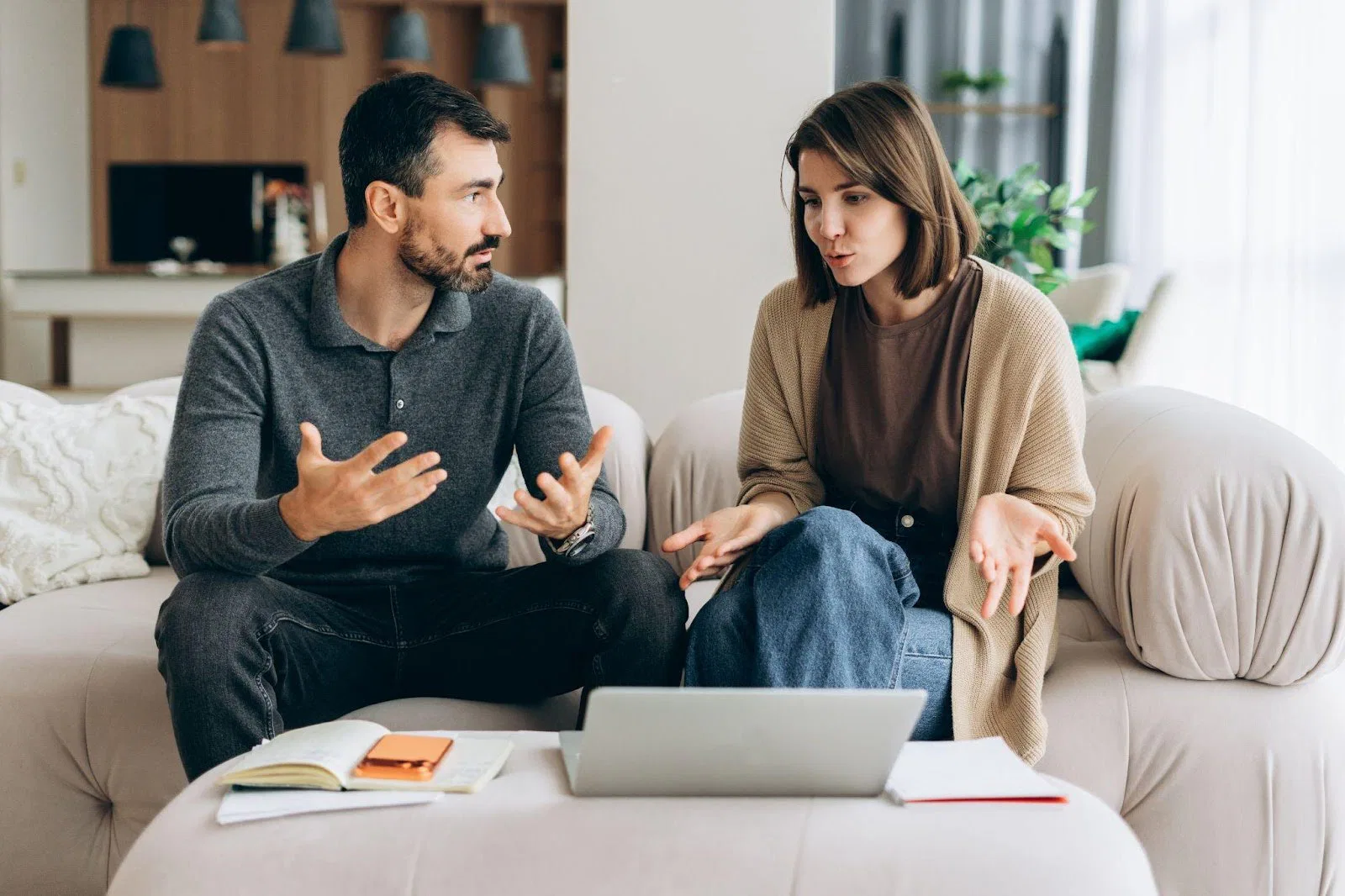 A couple engaged in conversation while sitting together on a couch in a cozy living room setting