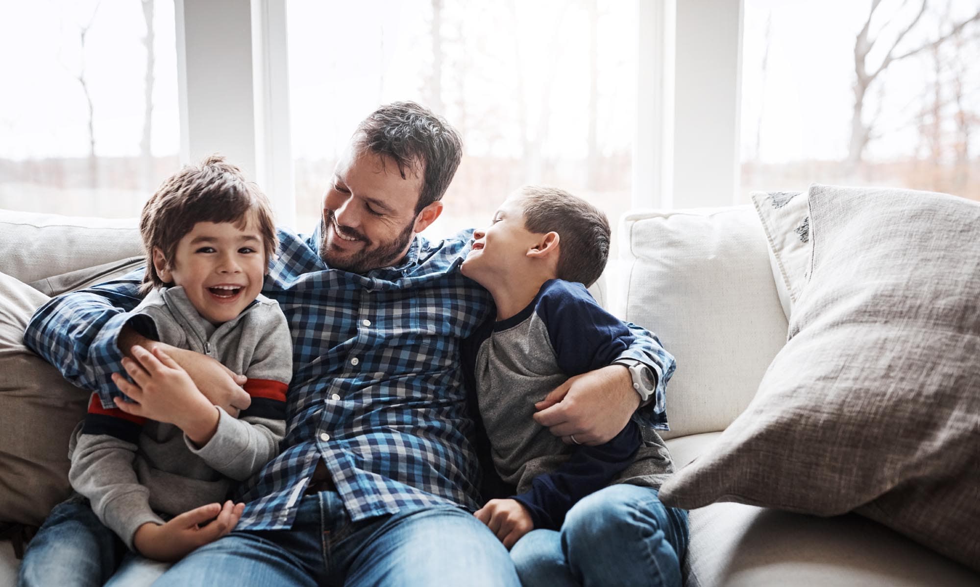A man and two boys sit together on a couch, representing the Burton Family Attorneys' focus on family law.