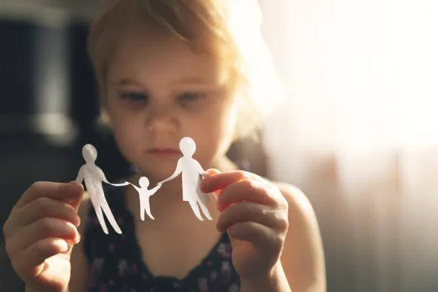 A little girl proudly displays a paper cutout of a family highlighting her artistic expression and joy