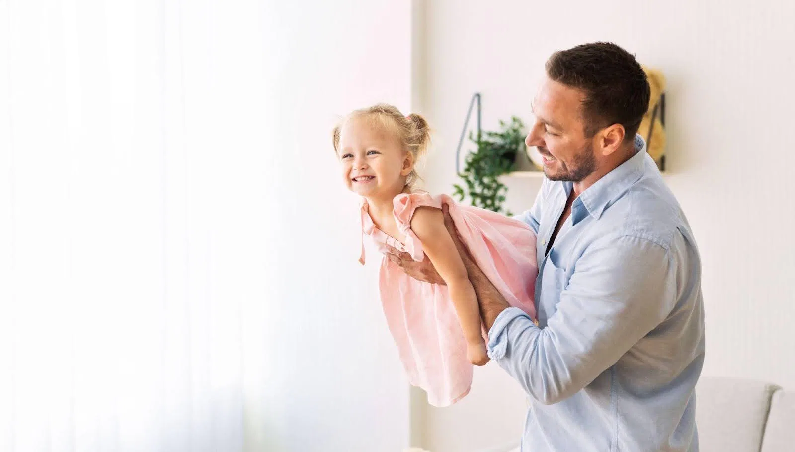 A man joyfully lifts a little girl into the air both smiling and enjoying a playful moment together