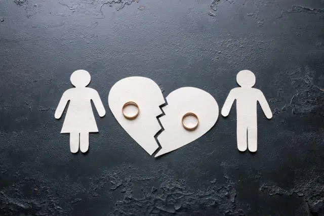 A broken heart with two individuals holding wedding rings symbolizing lost love and separation